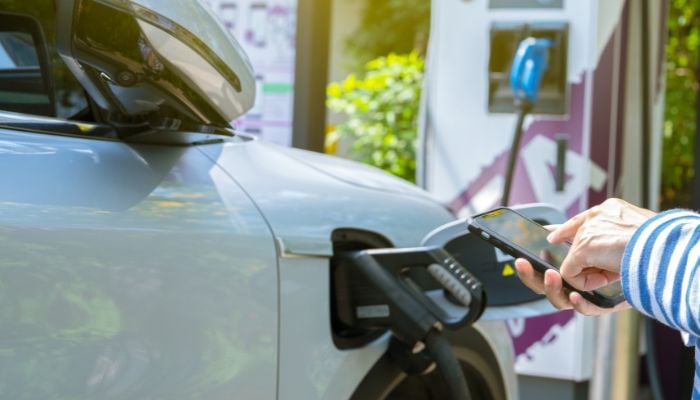An undated image of a person charging an EV cars. — Canva
