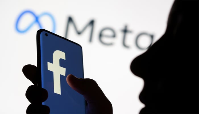 Woman holds smartphone with Facebook logo in front of a displayed Facebooks new rebrand logo Meta in this illustration picture taken October 28, 2021. — Reuters