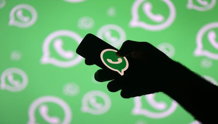 A man poses with a smartphone in front of displayed Whatsapp logo in this illustration September 14, 2017. — Reuters