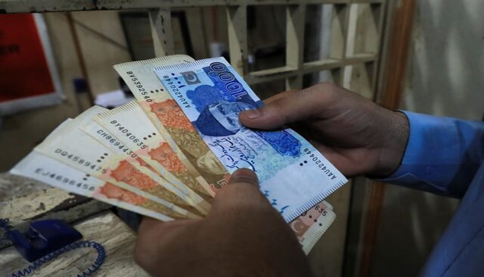 A man counts Pakistani rupee notes at a currency exchange shop in Peshawar, Pakistan September 12, 2023.