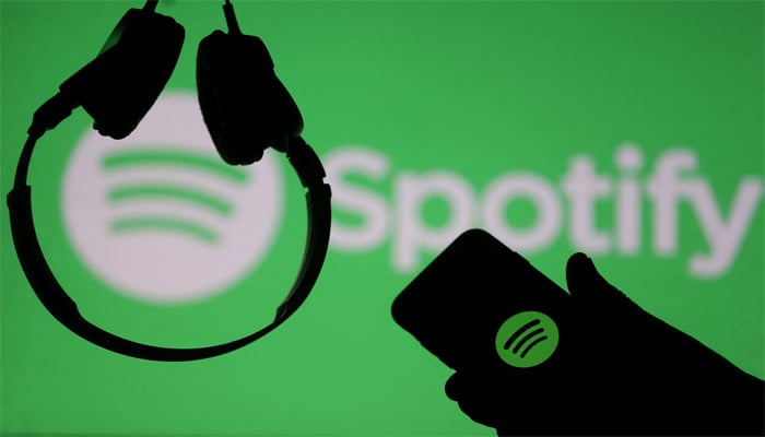 A smartphone and a headset are seen in front of a screen projection of Spotify logo, in this picture illustration taken April 1, 2018. — Reuters