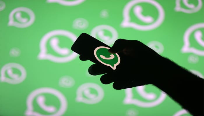 A man poses with a smartphone in front of displayed WhatsApp logo in this illustration September 14, 2017. — Reuters