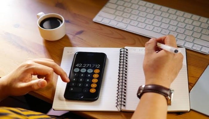 An undated image of a person using calculator app. — Freepik