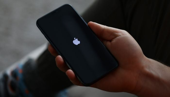 An undated image of a person holding iPhonne. — Canva