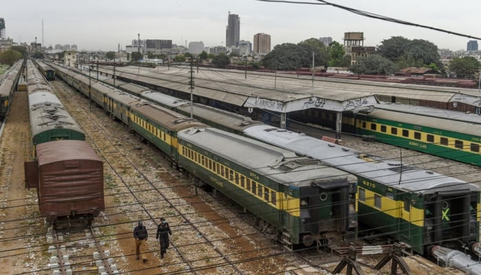 Policemen walk along trains stationed on a deserted platform at Karachi Cantonment railway station. — AFP