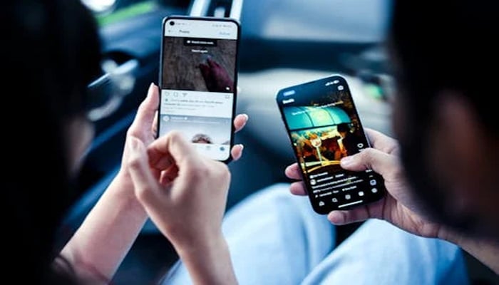 An undated image showing two persons watching Reels on Instagram. — Pexels