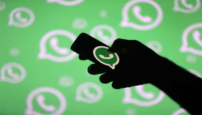 A man poses with a smartphone in front of displayed WhatsApp logo in this illustration September 14, 2017. — Reuters