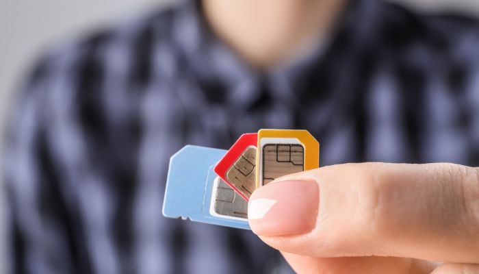 An undated image of a person holding SIMs. — Canva
